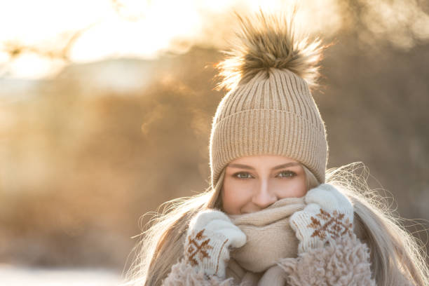 les jeunes femmes profitent d’un hiver ensoleillé. portrait en plein air d’une fille en écharpe et chapeau promenade dans un parc enneigé - femme froid photos et images de collection