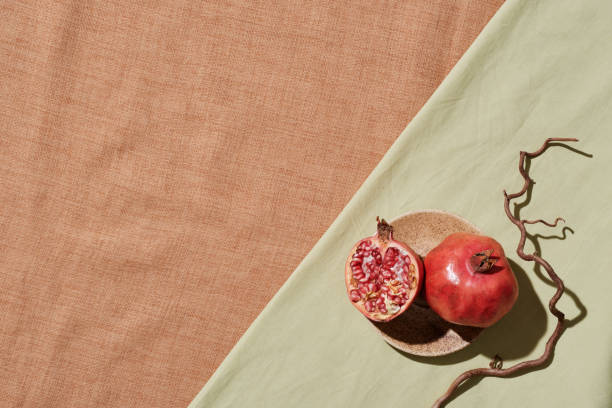 directly above view of ripe pomegranates on small plate placed on light green tablecloth with naked twig - plate food color image photography imagens e fotografias de stock