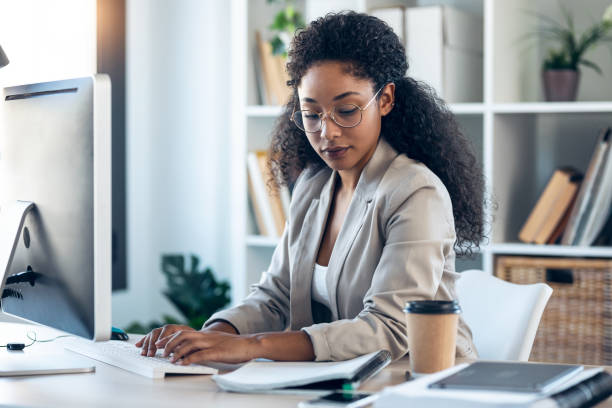 istock Elegant business woman working with laptop while checking and writing documents in the office. 1346245624