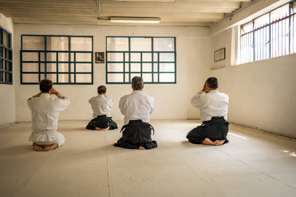 vier personen meditieren vor dem aikido-training - mexico only men senior men mature men stock-fotos und bilder