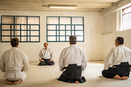 Four men meditate before aikido training