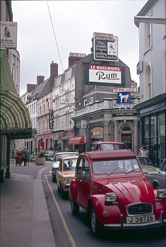 Saint Helier, Bailiwick of Jersey, UK, 1977. Street scene with cars, pedestrians, shops and buildings in Saint Helier, Bailiwick of Jersey.