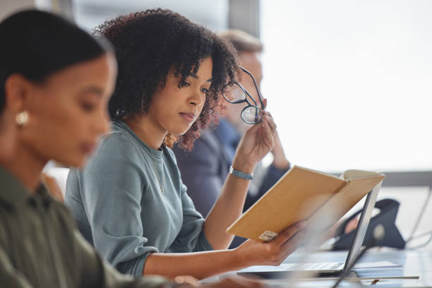 istock Shot of a young businesswoman going through notes while working alongside her colleagues in a call centre 1346251021