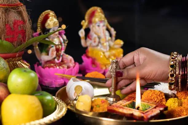 Hands Of Girl Holding Ghanti Bell. Clay Diya Deep Dia Lamp Illuminated In Pooja Thali For Aarti Of Maa Lakshmi & Bhagwan Ganesh Deva. Diwali Puja , New Year, Deepawali Or Shubh Deepavali Theme