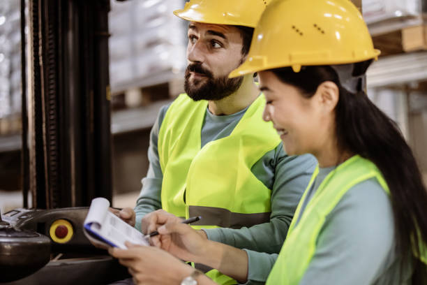 Checking the order Forklift driver talking with his Asian female manager in a large warehouse central asian ethnicity stock pictures, royalty-free photos & images