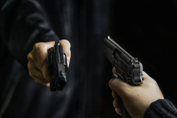 istock Two men's hands with weapons pointed at each other. 1346262419