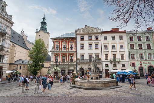 Lviv, Ukraine - Aug 17, 2019: Rynok Square (Market Square) with Neptune Fountain and Latin Cathedral Tower on background - Lviv, Ukraine