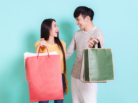 Happy couple with shopping bags.Looking at each other.Isolated on blue background.