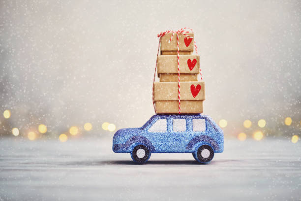 屋根の上にクリスマスプレゼントと雪の中で運転かわいいブルーグリッター車 - christmas stack gift carrying ストックフォトと画像