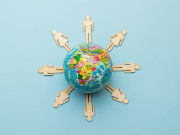 istock Wooden men around a model of the globe on a blue background. 1346281158