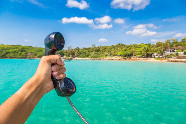 istock Hand holding handset, sea on background 1346284447