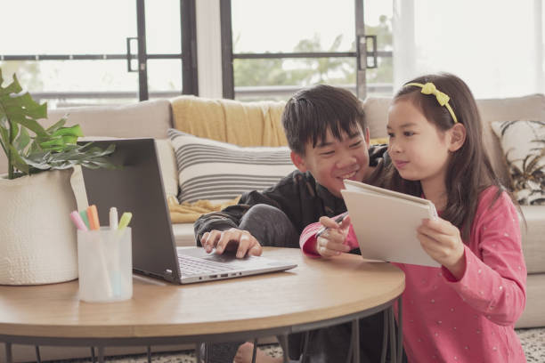 istock Mixed Asian girl making video calling with laptop at home, using zoom online virtual class , social distancing, homeschooling, remotely  learning during covid pandemic, new normal concept 1346284593