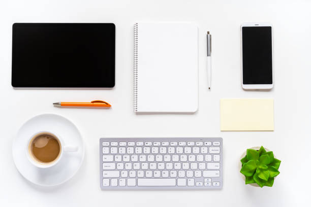 istock Office desk with a coffee cup, keyboard, digital tablet, smartphone, notebook, pen, green plant and sticky notes 1346287021
