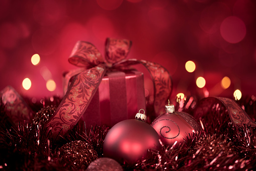 Christmas Gift and Baubles on a Red Background with Bokeh. Very shallow depth.