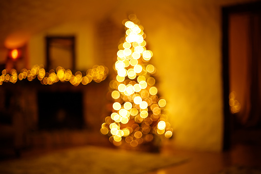 Warm christmas home room with christmas tree and festive bokeh lighting, blurred holiday background.