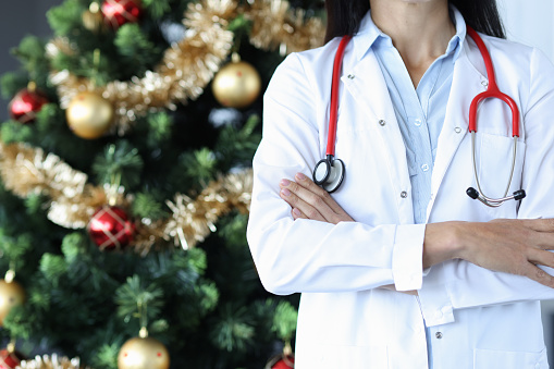 Mujer doctora con estetoscopio de pie cerca del primer plano del árbol de Navidad photo