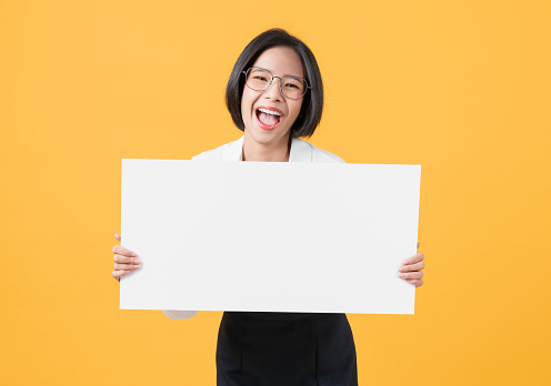 Young Asian woman holding blank paper with smiling face and looking on the orange background. for advertising signs.