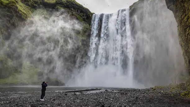 Photo of Young man taking photos of Skogafoss Waterfall Skógafoss Iceland