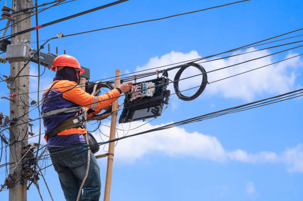 istock technician on wooden ladder is installing fiber optic system in internet splitter box on electric power pole against blue sky 1346303331