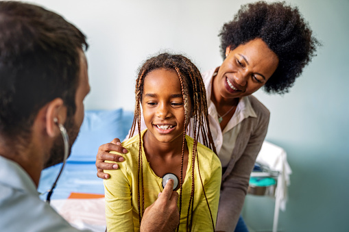 Healthcare medical exam people children and medicine concept. Close up of happy girl and doctor with stethoscope listening to heartbeat
