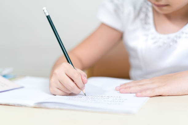 istock Cheerful Asian little girl children student writing on notebook doing homework and self study at home 1346308557