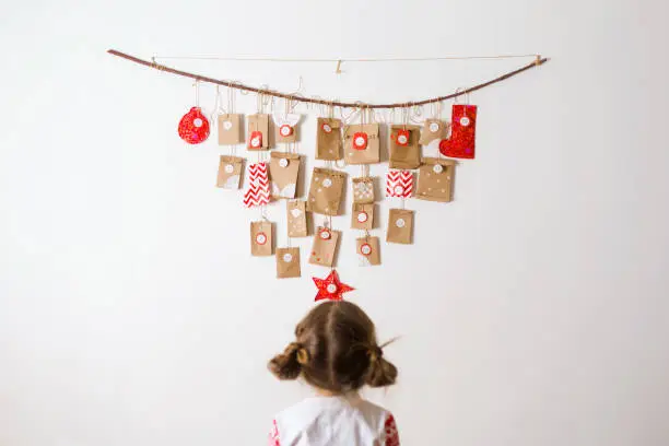 advent calendar hanging on wall. small surprises for kids. child looks at gifts.