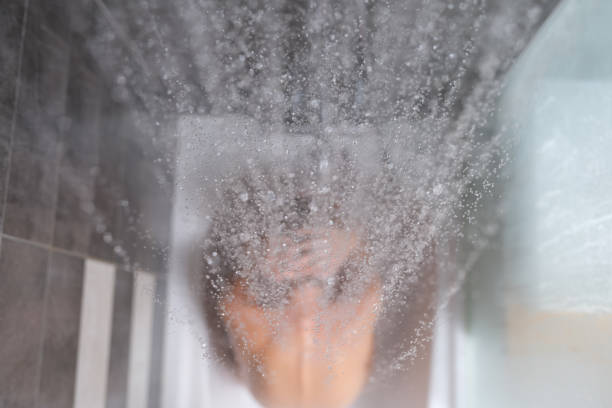 женщина сидит в ванне, вода выливается сверху на спину крупным планом - mistic стоковые фото и изображения