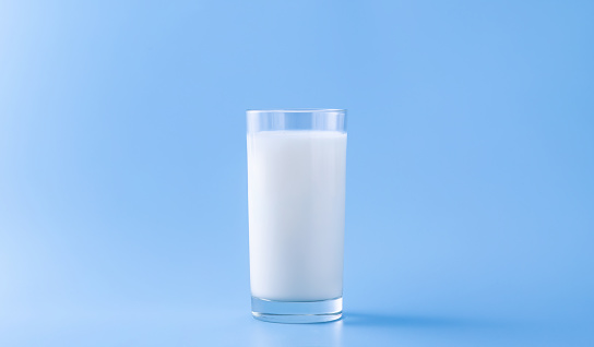 milk is poured into a glass on a blue background splash splash of milk