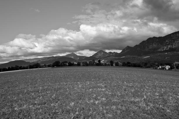 Extensive fields in the French Alps surrounding an opulent farmhouse in black and white