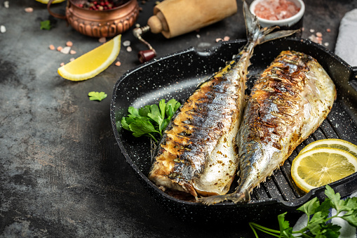 baked mackerel fish in a pan with lemon herbs and spices, banner, menu recipe place for text, top view,