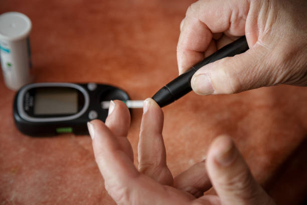 puncturing finger with lancet for measuring blood sugar with glaucometer - glaucometer imagens e fotografias de stock