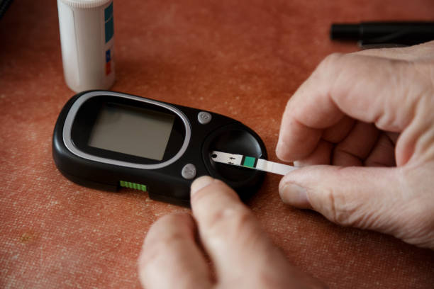 putting test strip into glaucometer for measuring blood sugar - glaucometer imagens e fotografias de stock