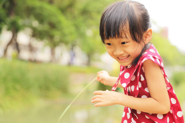 a smiling Asian girl playing in a park .