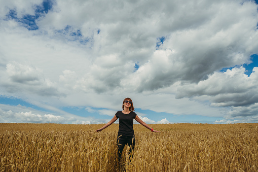 Field. A girl walks through a yellow wheat field.