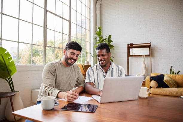 Young gay couple smiling while going over their finances together stock photo