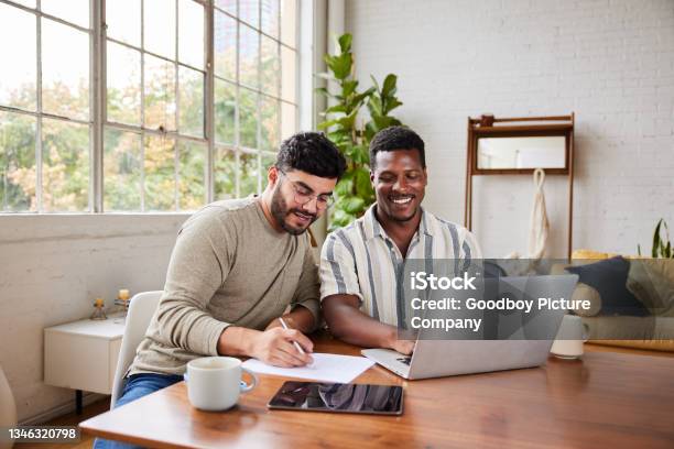 Smiling Young Gay Couple Going Over Their Home Finances Together Stock Photo - Download Image Now
