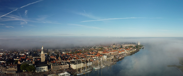 Kampen city view at the river IJssel during a foggy sunrise at the start of an autumn day with mist and blue skies.Kampen is an ancient Hanseatic League city at the shore of the river IJssel in Overijssel, The Netherlands.