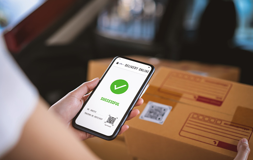 Startup small business, hand using smartphone with scan QR code on cardboard box delivery for products to send to customers.