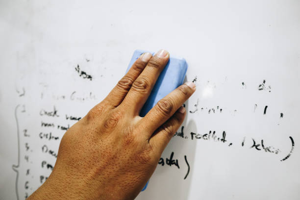 hand of a man erasing the whiteboard. a hand holding a whiteboard eraser.