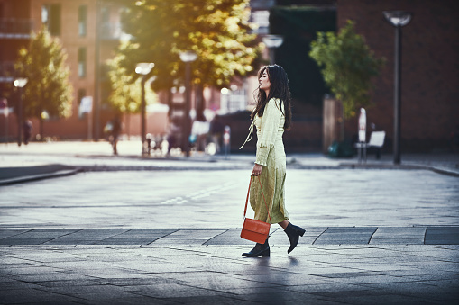 Model outdoors in city / street. Asian woman in green dress walking