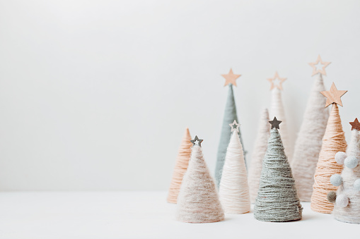 Christmas craft background with handmade yarn cone xmas trees in natural colors. DIY organic sustainable christmas decoration