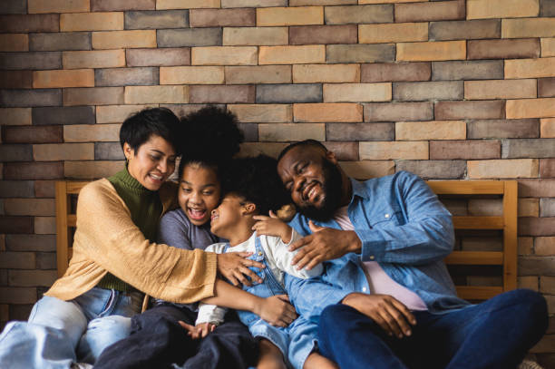 Happy African American family have fun teasing each other. Father and mother tickled their two daughters. Mum, dad and girls laughing and hugging. family relationship stock photo