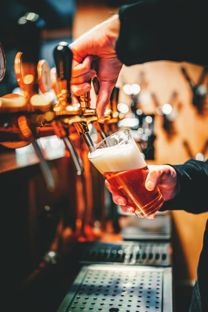 istock bartender hand at beer tap pouring a draught beer in glass serving in a bar or pub 1346324984