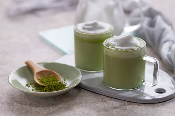 Green tea matcha latte with milk foam in a cup and powed matcha stock photo