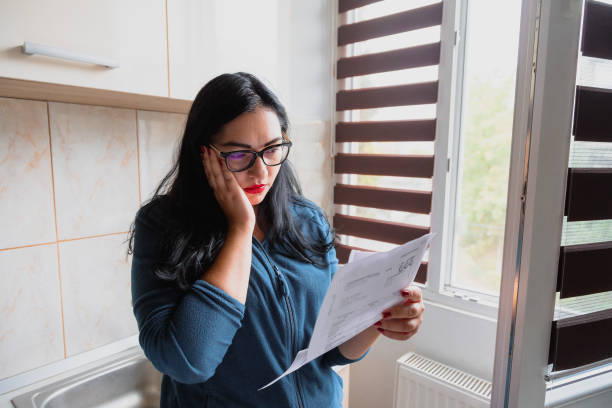 femme inquiète vérifiant les factures à la maison - équipement à base de papier photos et images de collection