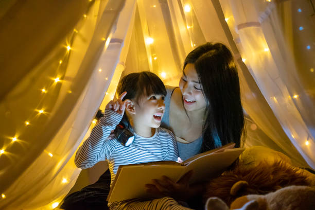 la madre leía cuentos de hadas para que su hija los escuchara en casa. - oriental tent fotografías e imágenes de stock