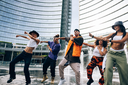 Young multiethnic performers dancing with Rap music in the city streets.
