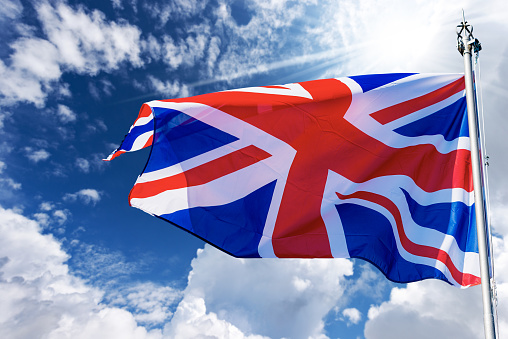 A large UK flag flying in the wind.