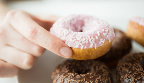 istock close up of hand holding glazed donut 1346329905