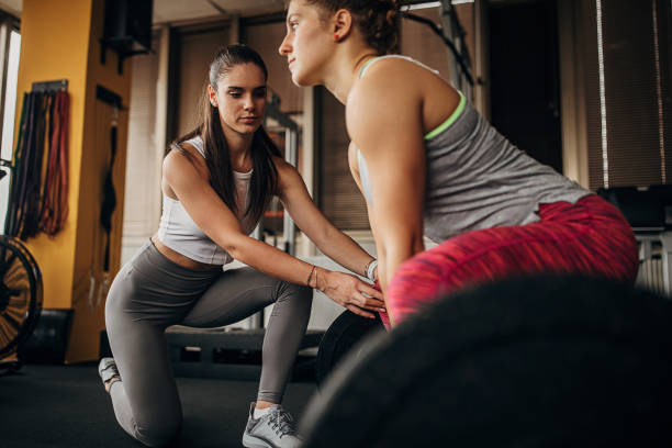 istock Personal trainer assisting a young woman in weightlifting 1346330966